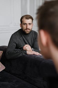 A thoughtful therapist listens attentively to a patient during a counseling session in a modern office.