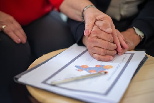 Two adults holding hands over business documents, symbolizing support and partnership.